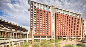 A modern hotel with a prominent red facade, multiple floors, and a large glass entrance.