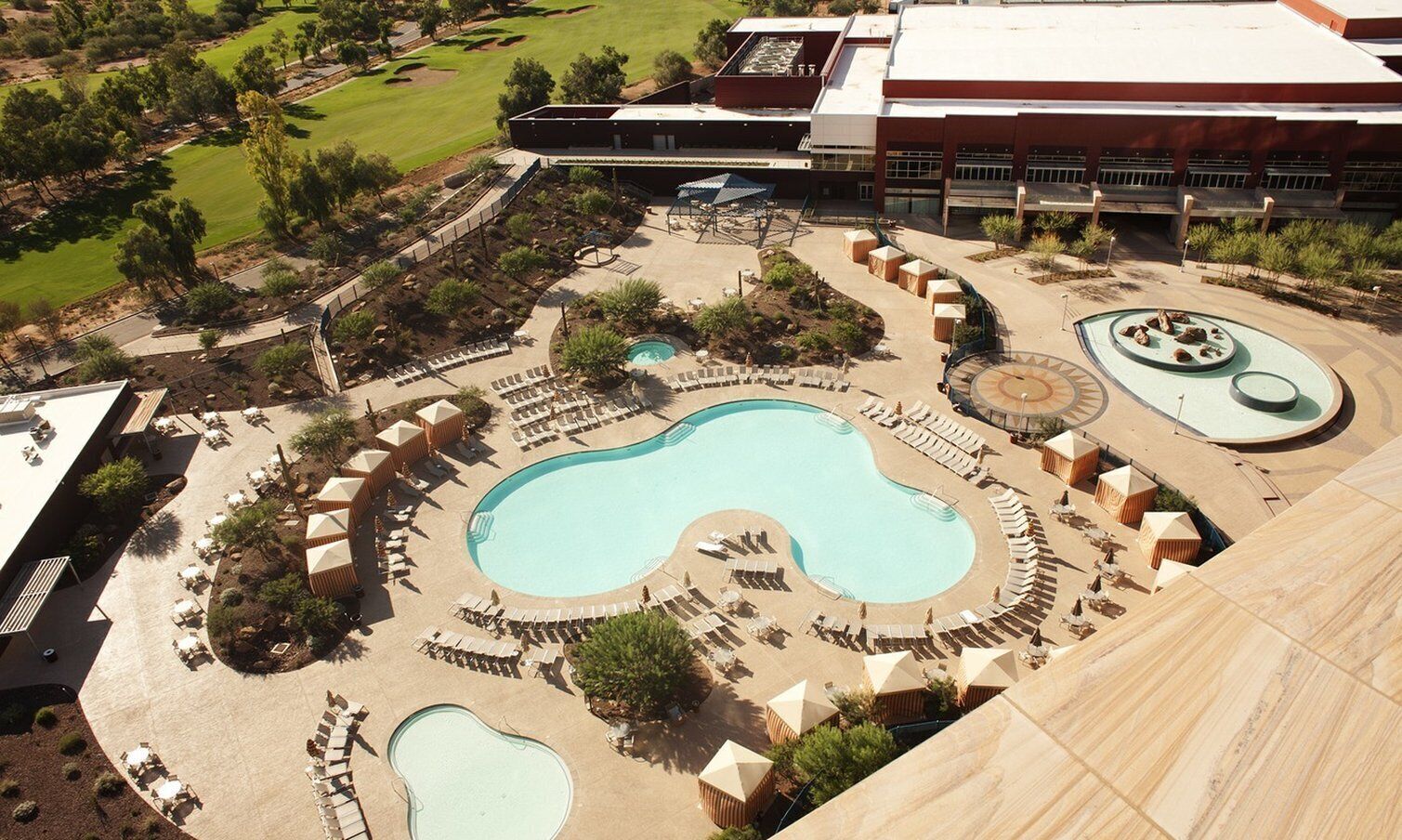 A resort with a large central pool, multiple smaller pools, and sun loungers arranged around the pools.