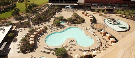 A resort with a large central pool, multiple smaller pools, and sun loungers arranged around the pools.