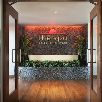 A reception area with a mosaic wall, a reception desk, and two potted cacti.