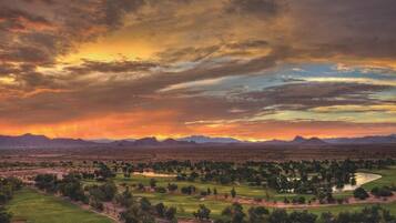 A golf course with a panoramic view of mountains and a sunset.