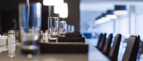 A modern hotel conference room with a long table, chairs, and a row of lamps.