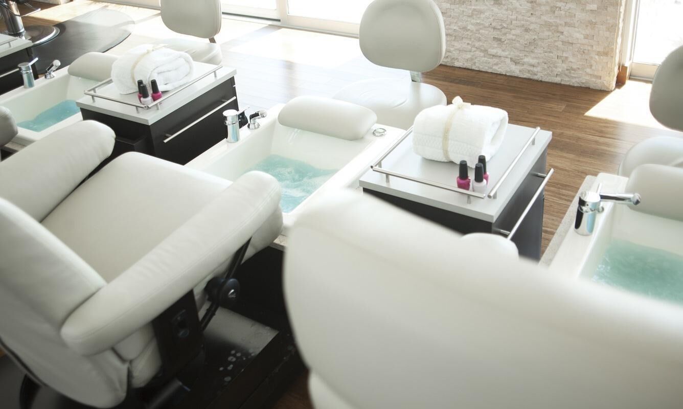 Una moderna spa con diverse poltrone per trattamenti, ognuna dotata di vasca per i piedi e asciugamani.