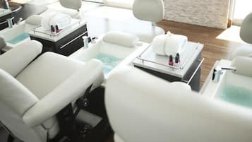 A modern spa room with multiple treatment chairs, each equipped with a foot bath and a towel.