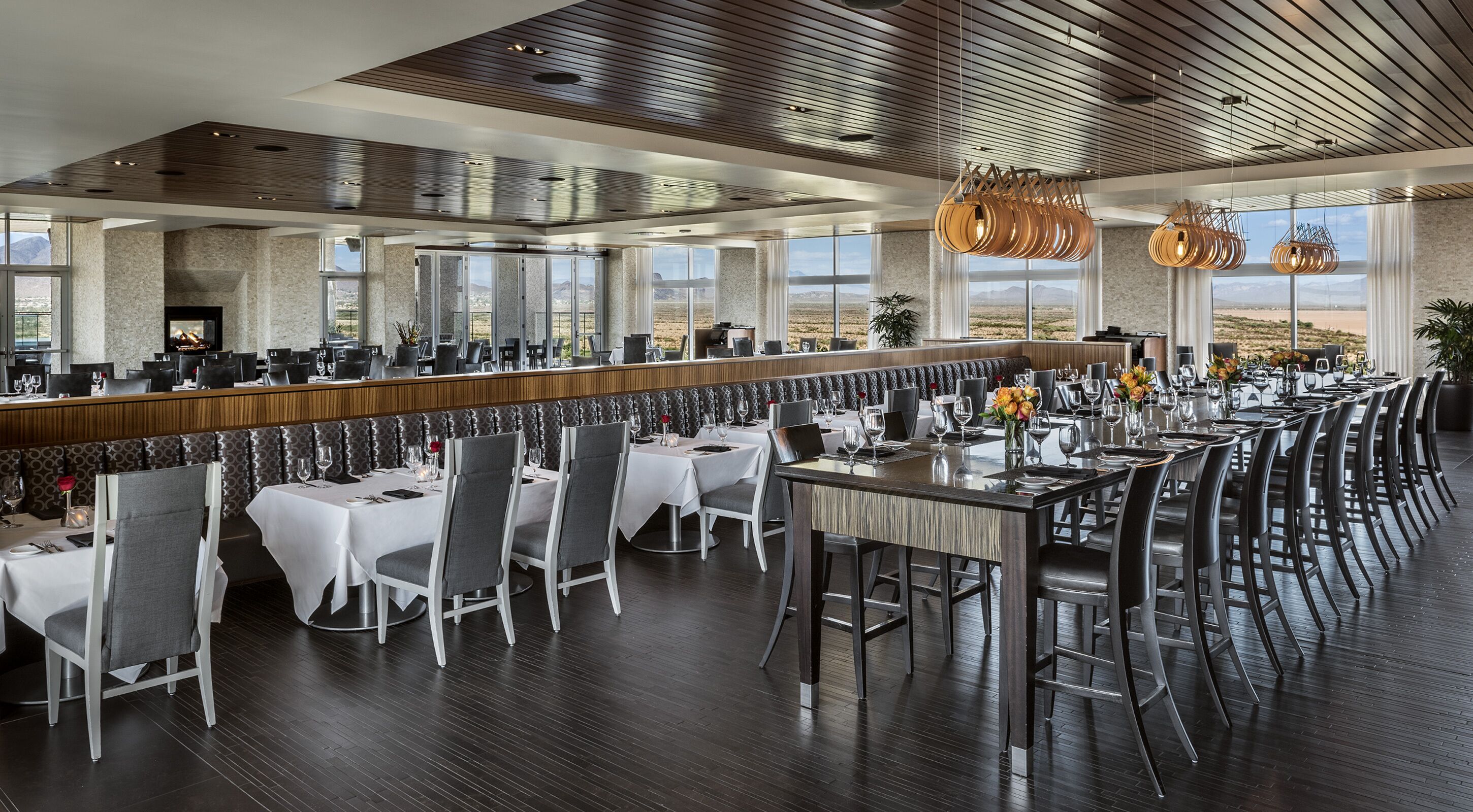 Un'ampia sala da ristorante con soffitti alti, grandi finestre e un arredamento moderno.