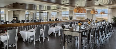 A spacious restaurant with high ceilings, large windows, and a modern interior design.