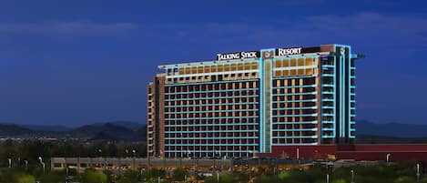 A large hotel with multiple floors, a prominent sign reading "Talking Stick Resort," and a parking area in the foreground.