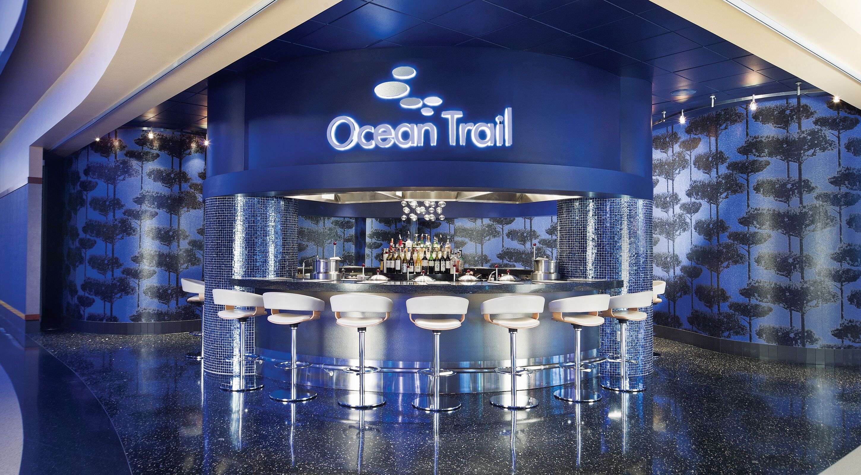 A bar area with a sign reading "Ocean Trail" and a bar counter with multiple stools.