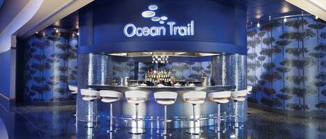 A bar area with a sign reading "Ocean Trail" and a bar counter with multiple stools.