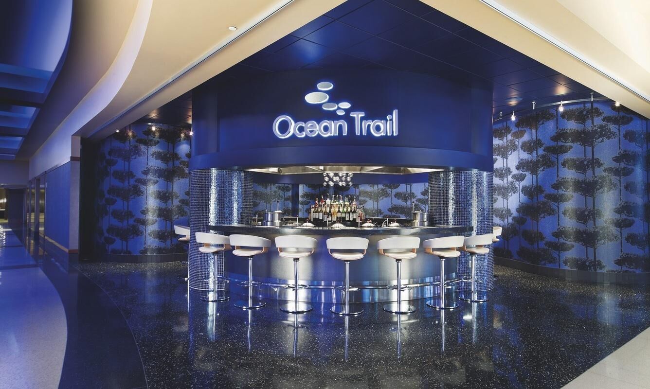 A bar area with a sign reading "Ocean Trail" and a bar counter with stools.