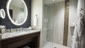 Un baño moderno con tocador de mármol, un espejo grande, cabina de ducha con mampara de cristal y un perchero para toallas.