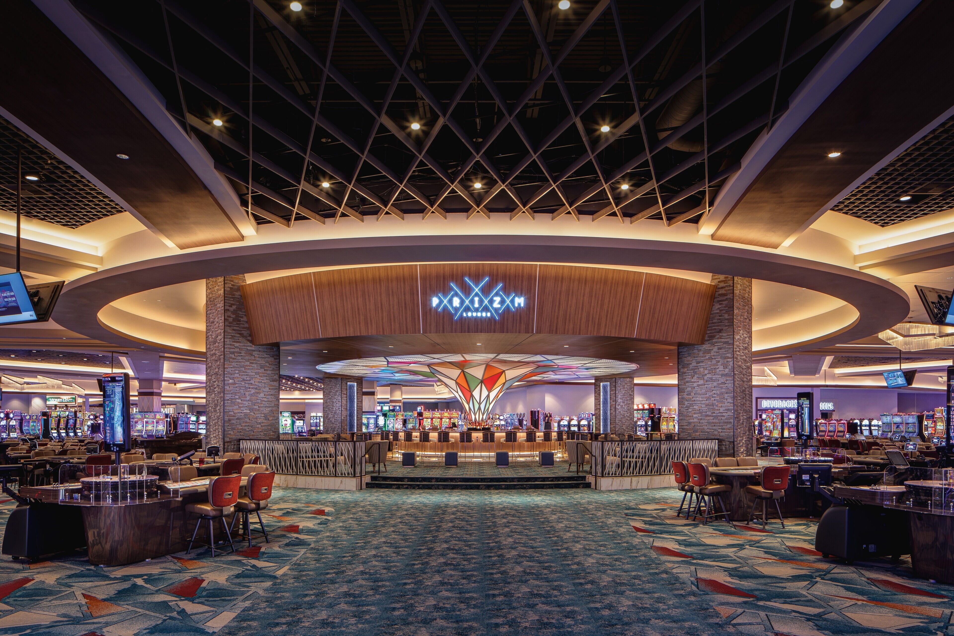 Eine großzügige Casino-Lobby mit einer zentralen Bar, mehreren Spielautomaten und einem markanten Deckenstil.