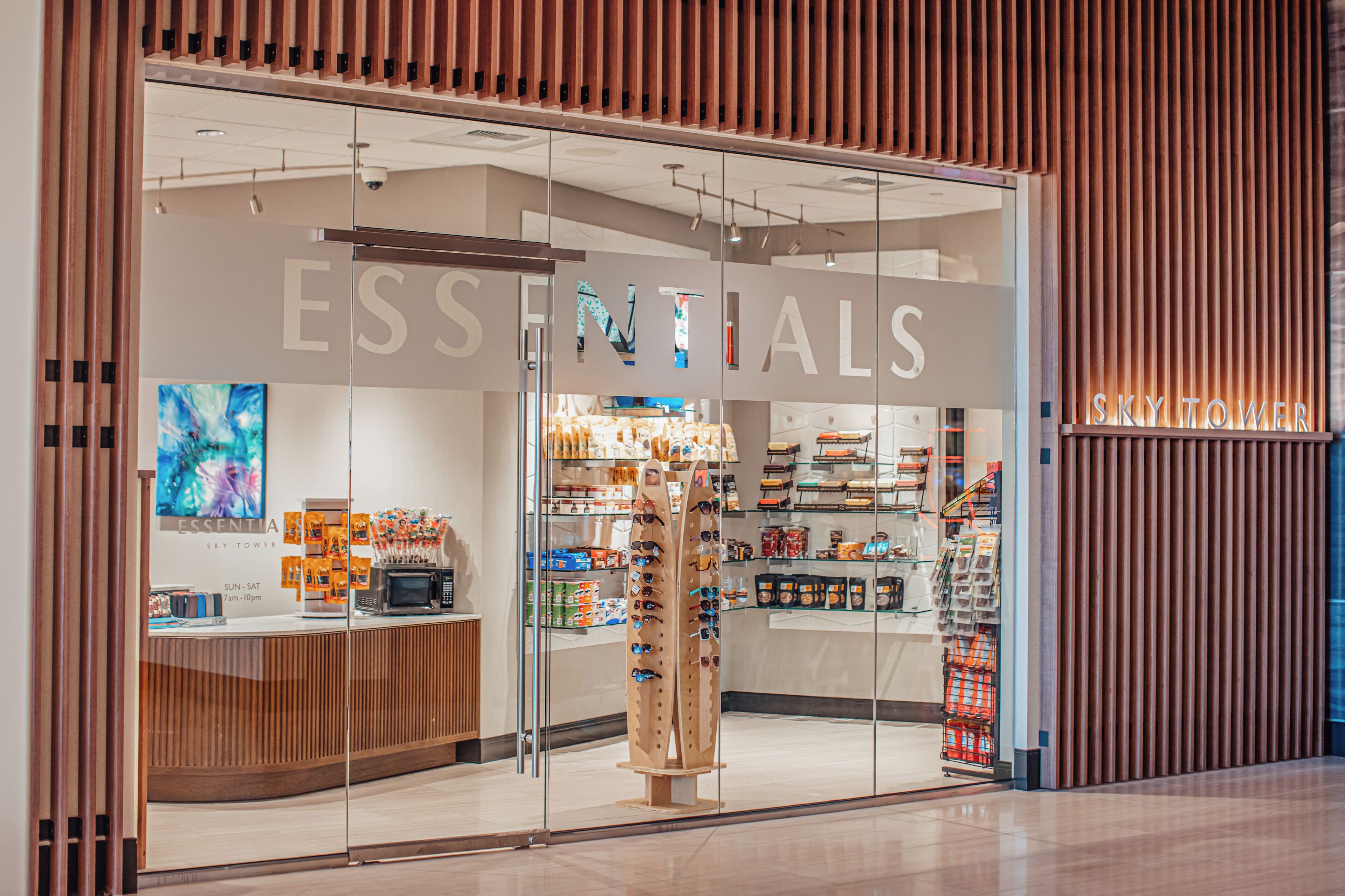 A store named 'ESSENTIALS' with a modern interior, glass display windows, and a wooden facade.
