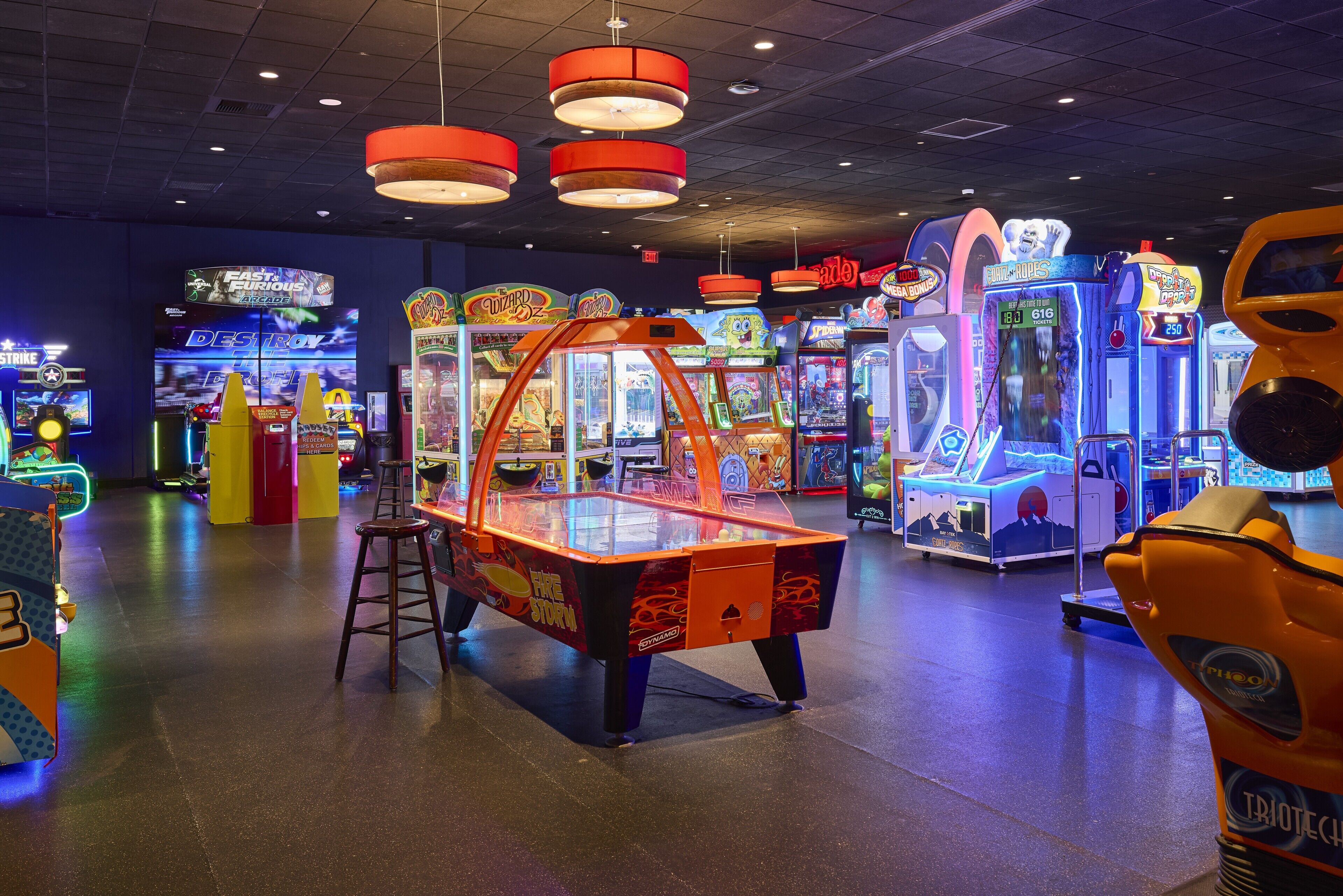 An indoor arcade with various gaming machines, including a claw machine and racing games.