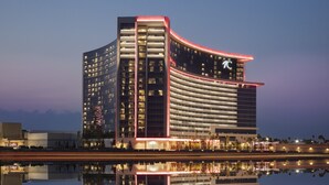 A modern hotel with a curved facade, multiple floors, and a prominent 'I' logo. - Choctaw Casino & Resort Durant, a Wyndham Grand Hotel (Durant)