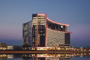 Un hotel moderno con fachada curva, varios pisos y un llamativo logo 'I'.