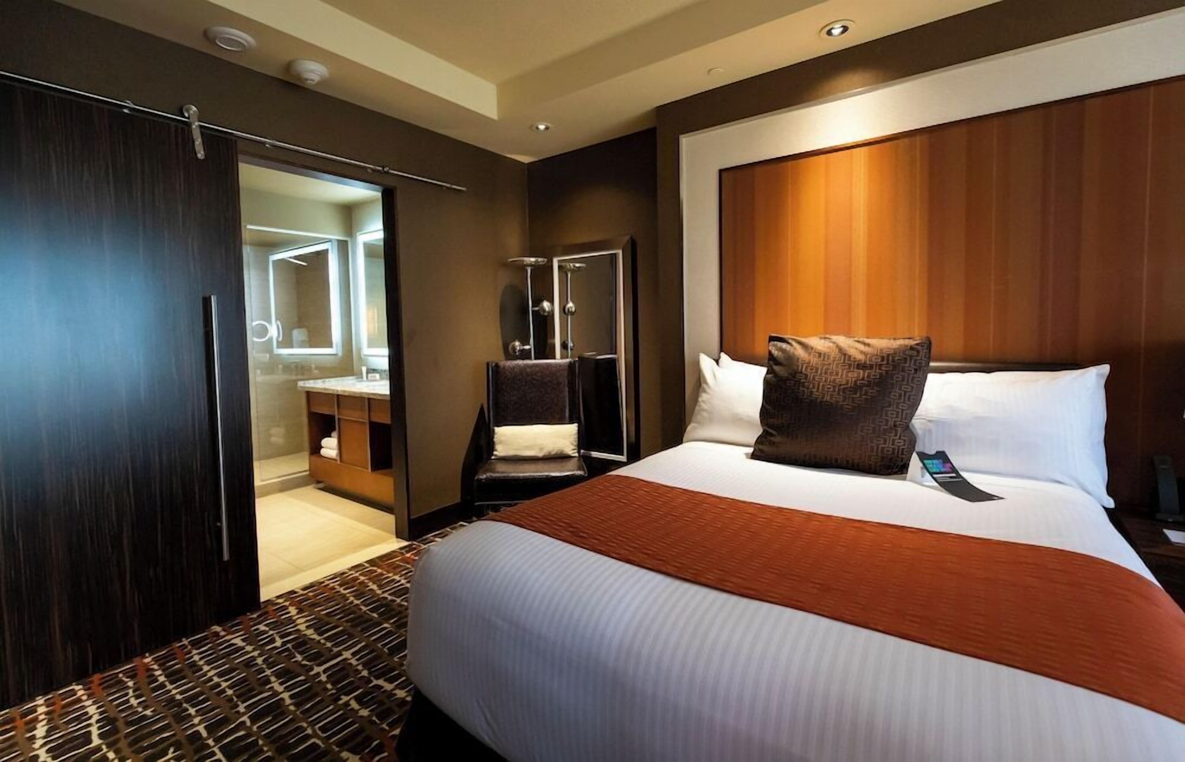 Een hotelkamer met een groot bed, een kledingkast, een badkamer en een spiegel.