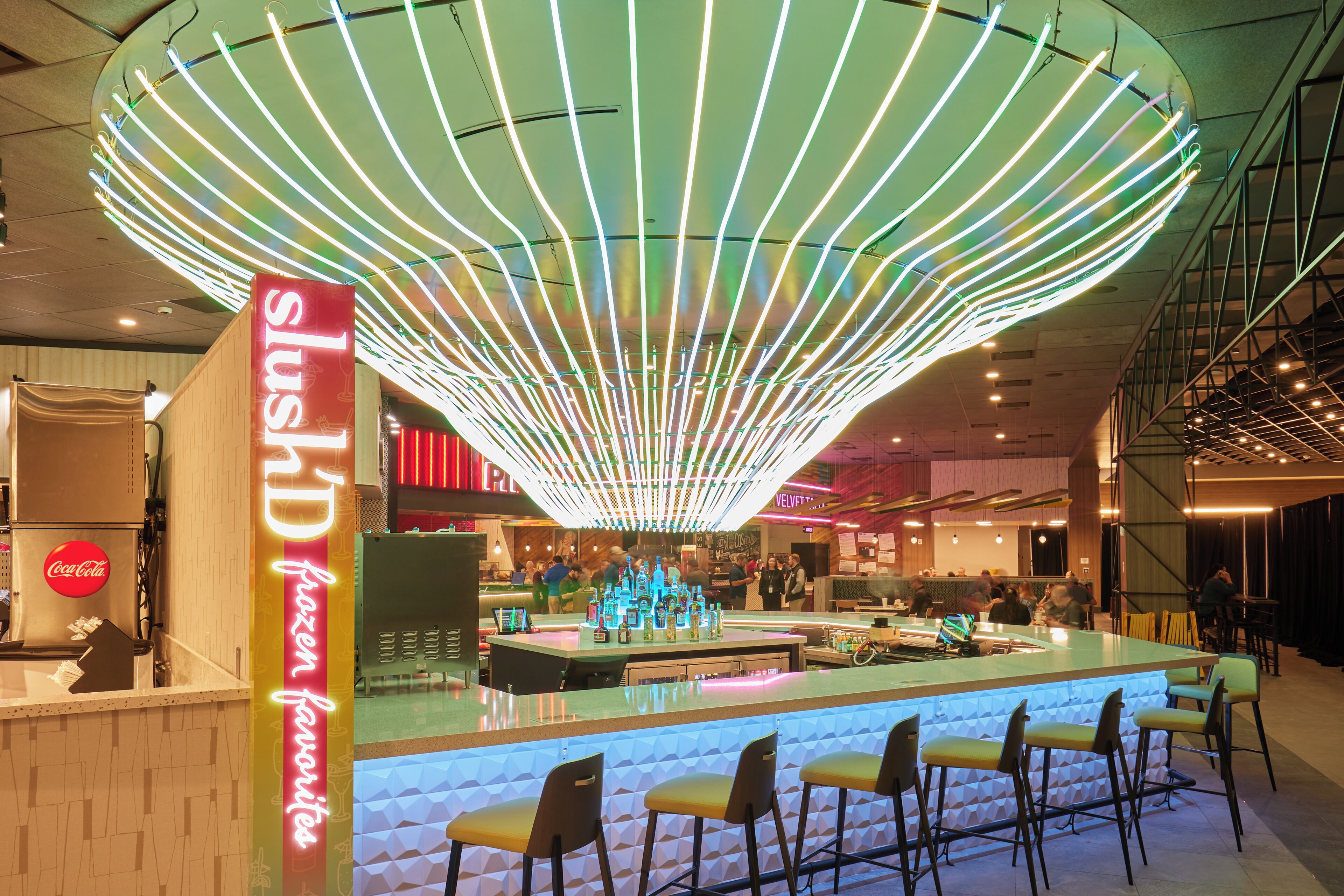 A bar area with a neon sign, a Coca-Cola machine, and a seating arrangement.