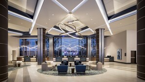 A spacious lobby with a modern chandelier, seating area, and large windows offering a view of the city. - Choctaw Casino & Resort Durant, a Wyndham Grand Hotel (Durant)