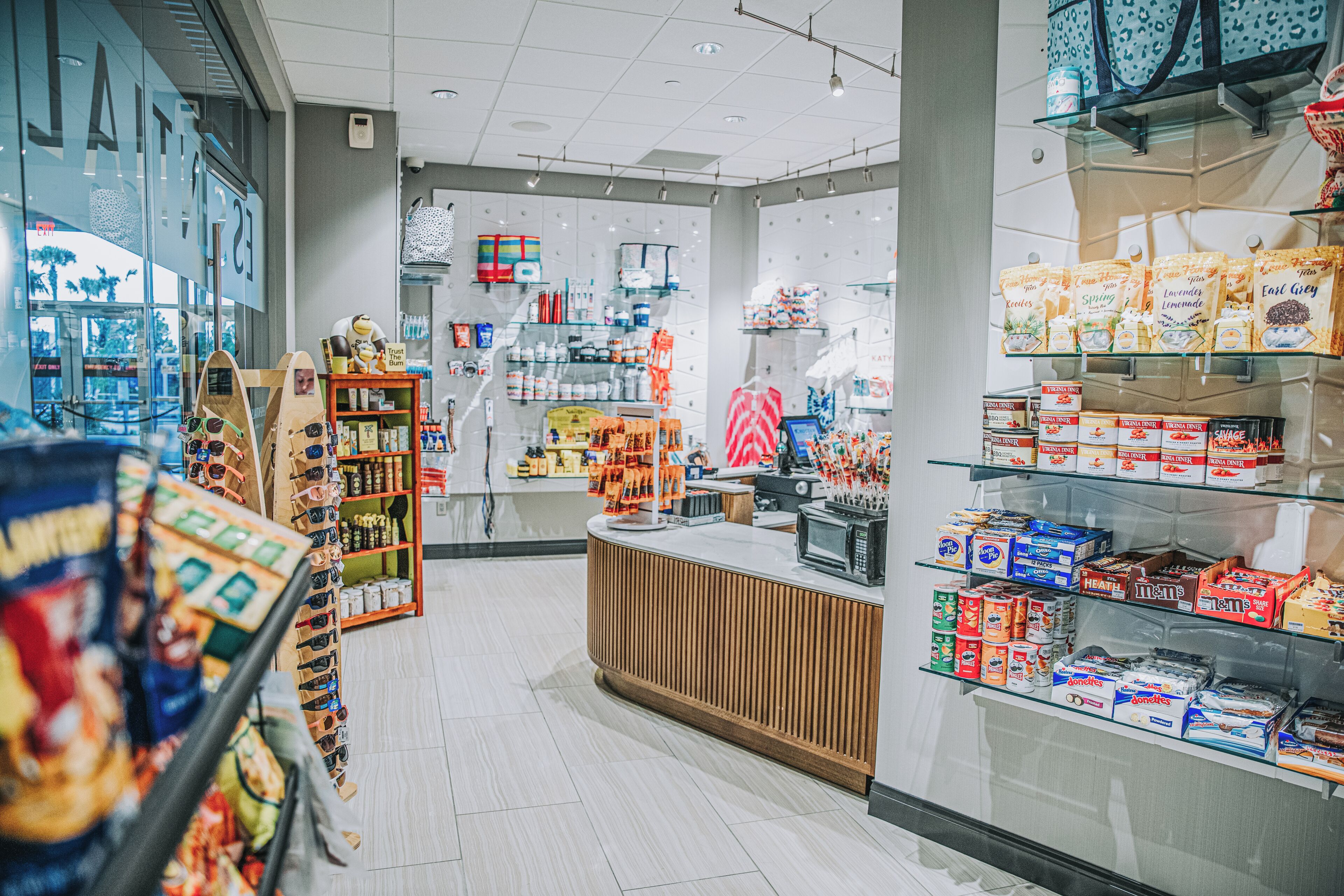 A store interior with shelves stocked with various products, a wooden counter, and a glass display case.