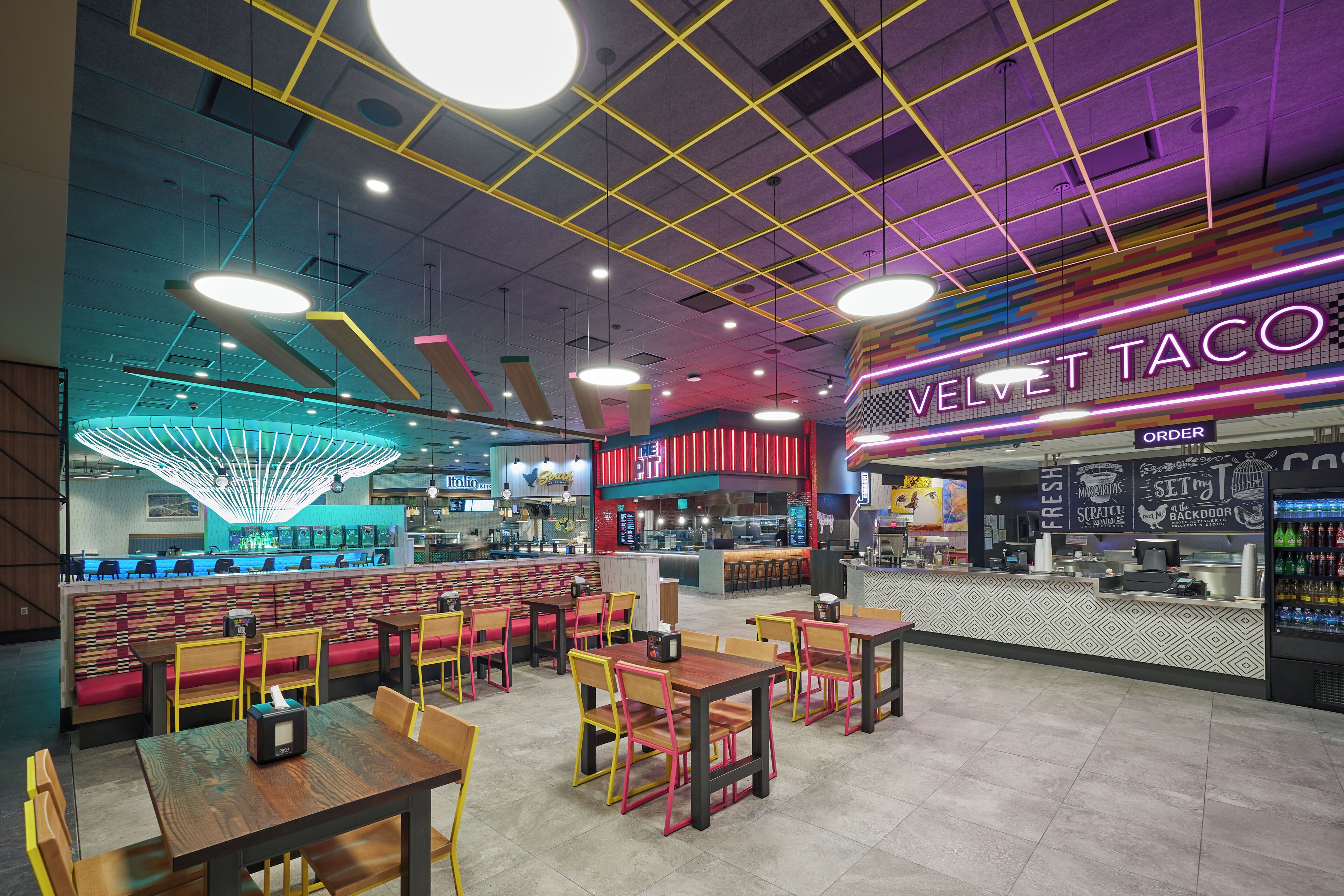 A restaurant interior with booths, tables, and a neon sign for Velvet Taco.