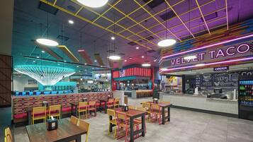 A restaurant interior with booths, tables, and a neon sign for Velvet Taco.