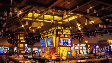 A bar area with multiple gaming machines, a bar counter, and hanging light fixtures.