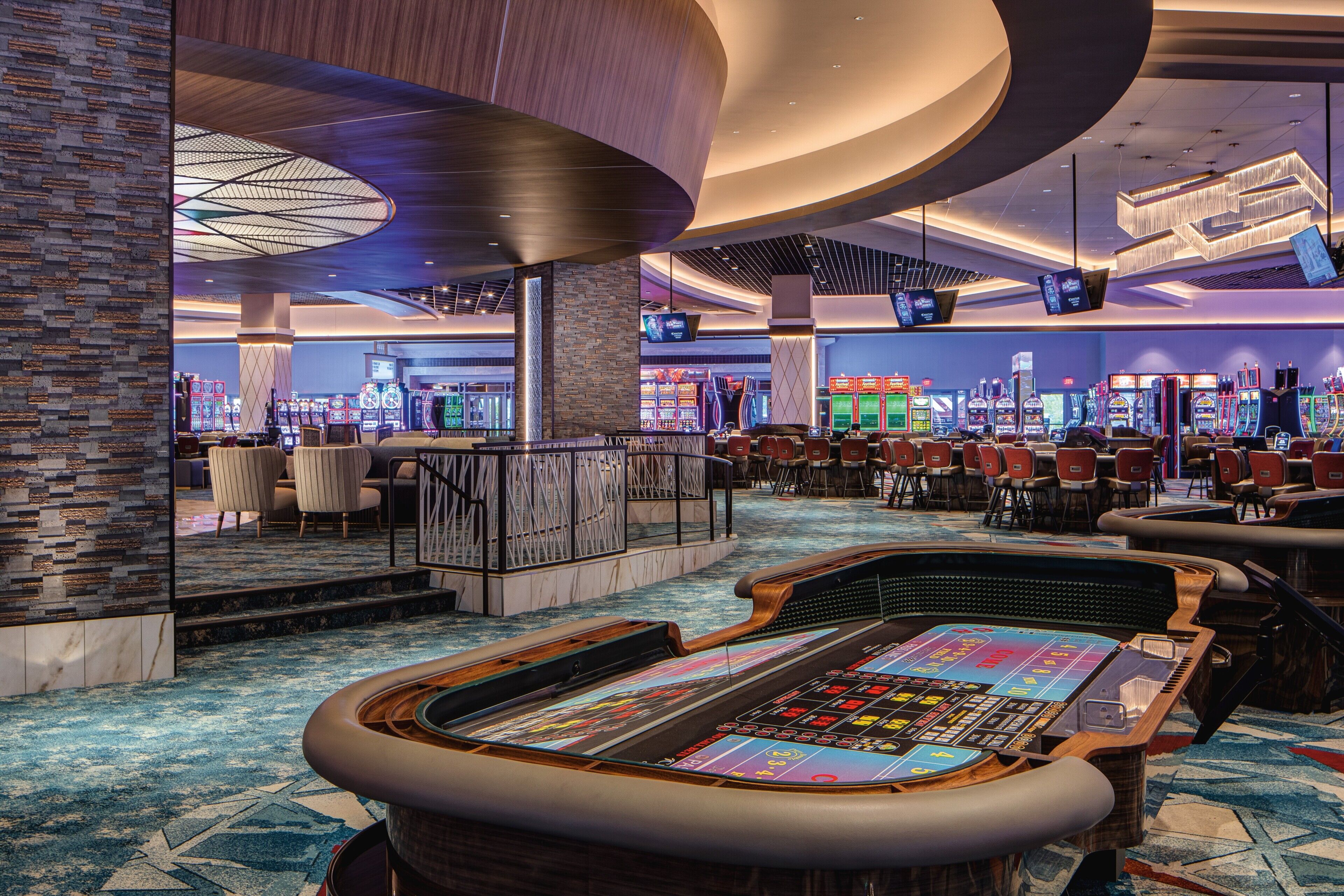 Un casinò con un ampio tavolo da craps, diverse slot machine e un design d'interni moderno.