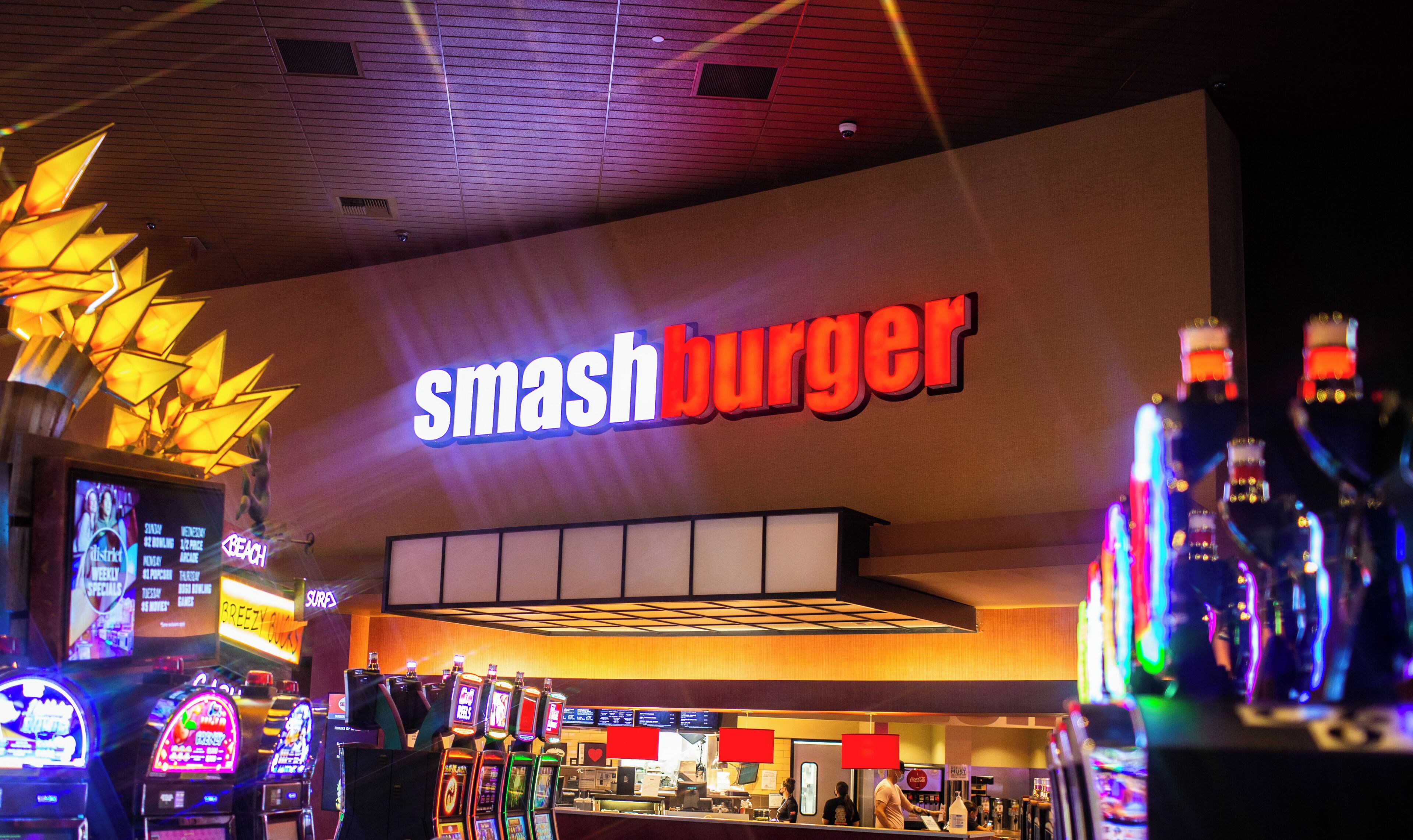 Letrero de Smash Burger, máquinas de videojuegos y una zona de mostrador.