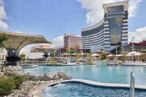 Un hotel con piscina, bañera de hidromasaje y una estructura de techo de paja.