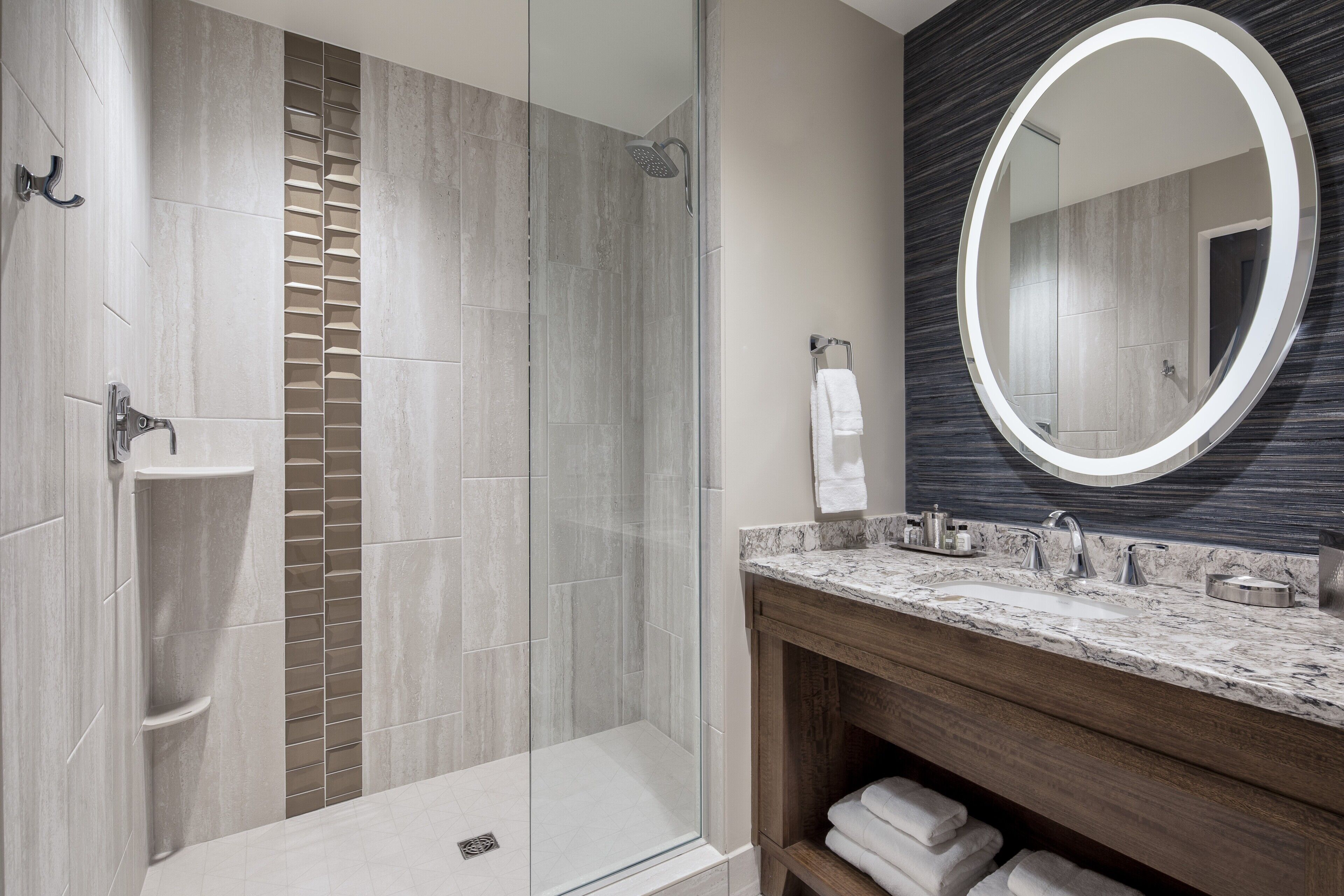 A modern bathroom with a glass-enclosed shower, a marble sink, and a large mirror.