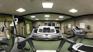 Et fitnesscenter med løbebånd, spinningcykel og romaskine.