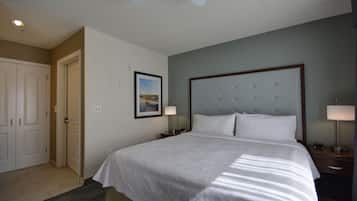 A hotel room with a large bed, a ceiling fan, a framed picture on the wall, and a door to the left.