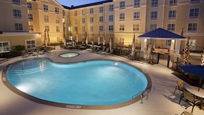A hotel courtyard with a swimming pool, lounge chairs, and a covered seating area. - Homewood Suites Wilmington/Mayfaire (Wilmington)