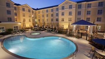 Una piscina al aire libre, sombrillas, sillones reclinables de piscina