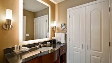 A hotel bathroom with a large mirror, a sink, and a towel rack.