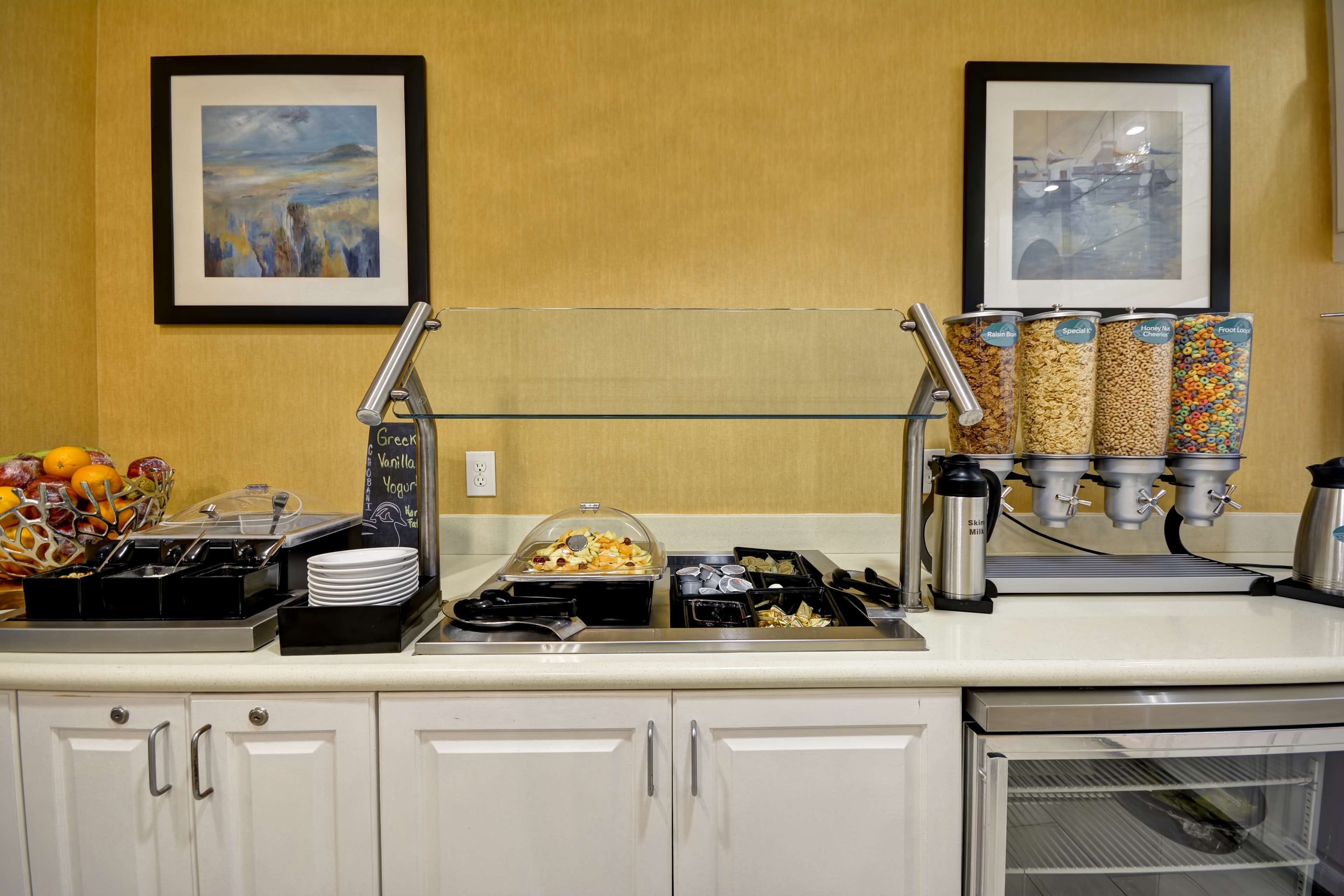 A breakfast bar with various food options, including cereal and yogurt, and a fruit basket.