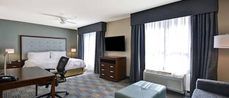 Una habitación de hotel con cama, escritorio, silla, televisor y sofá.