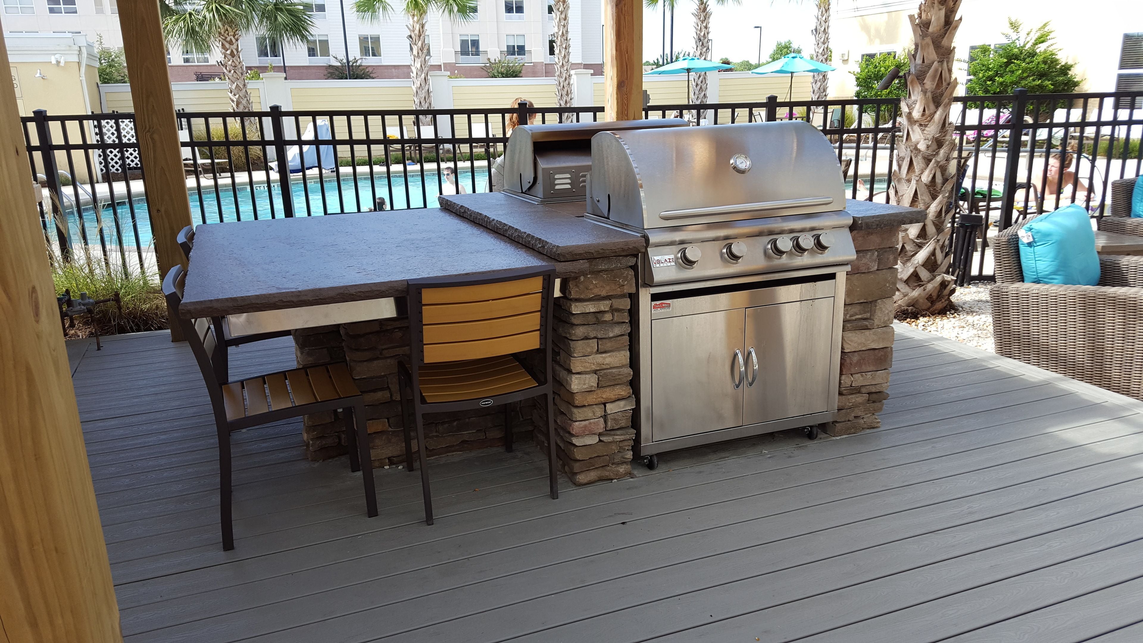 An outdoor barbecue area with a grill, a table, and chairs.