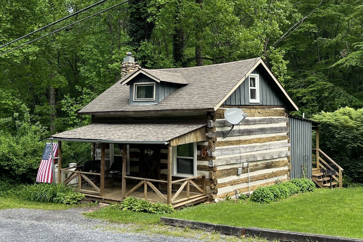 A rustic log cabin with a porch, a chimney, and a satellite dish.