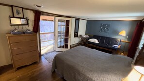 A hotel room with a bed, a dresser, a mirror, a window with curtains, and a wall decoration. - Cabin Creekwood (Lyndhurst)
