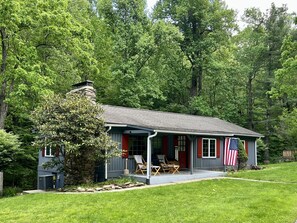 A small house with a porch, an American flag, and a stone chimney. - Cabin Creekwood (Lyndhurst)