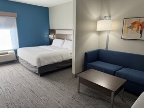 A hotel room with a bed, a blue sofa, a small table, and a lamp. - Holiday Inn Express & Suites Topeka North by IHG (Topeka)