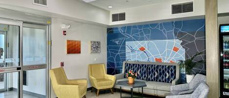 A modern lobby with seating, a map mural, and a vending machine.