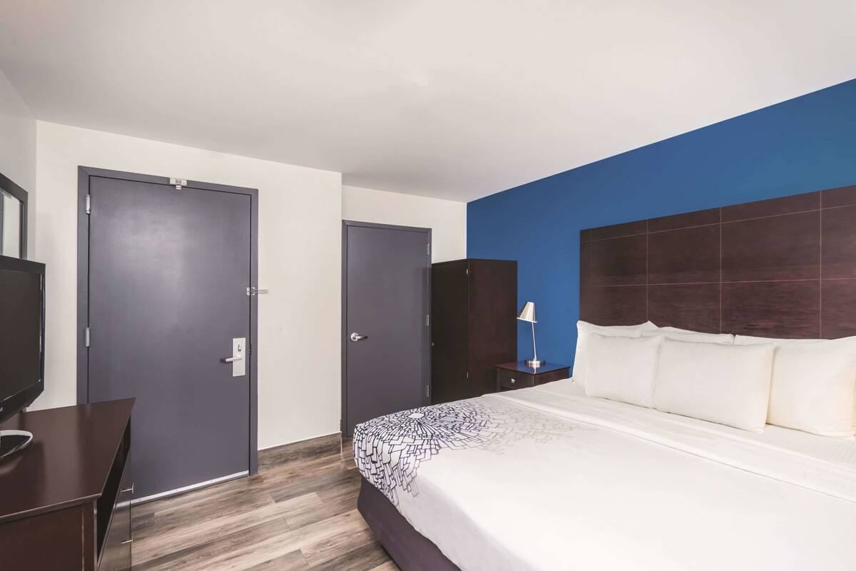 Une chambre d’hôtel avec un lit, une télévision, une armoire et un bureau.