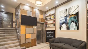 A modern living room with a sofa, a staircase, a flat-screen TV, and a welcome sign.