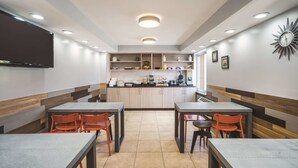 A restaurant with tables and chairs, a counter with a display, and a clock on the wall.