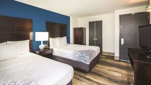 A hotel room with two beds, a TV, a desk, and a wardrobe.