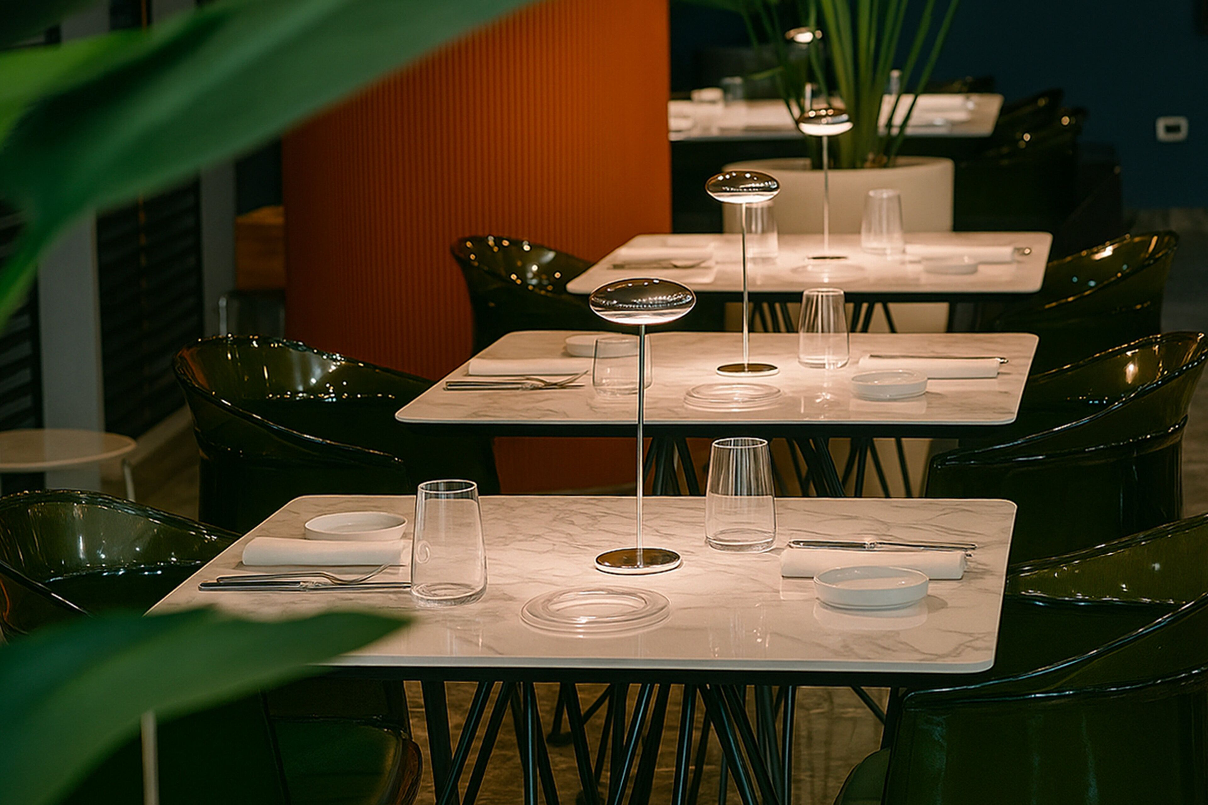 A restaurant with tables set for dining, featuring clear glassware and plates.