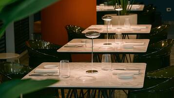 Restaurante com mesas montadas para refeições, com copos e pratos transparentes.